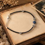 Load image into Gallery viewer, Retro Evil Eye black crystal beaded oxidized silver anklet with floral charms, adjustable vintage boho payal for women, handcrafted minimalist ethnic fashion jewelry.