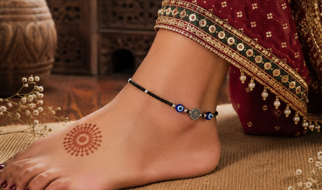 Indian woman wearing a handcrafted evil eye crystal oxidized silver anklet with black beads and blue protective charms.