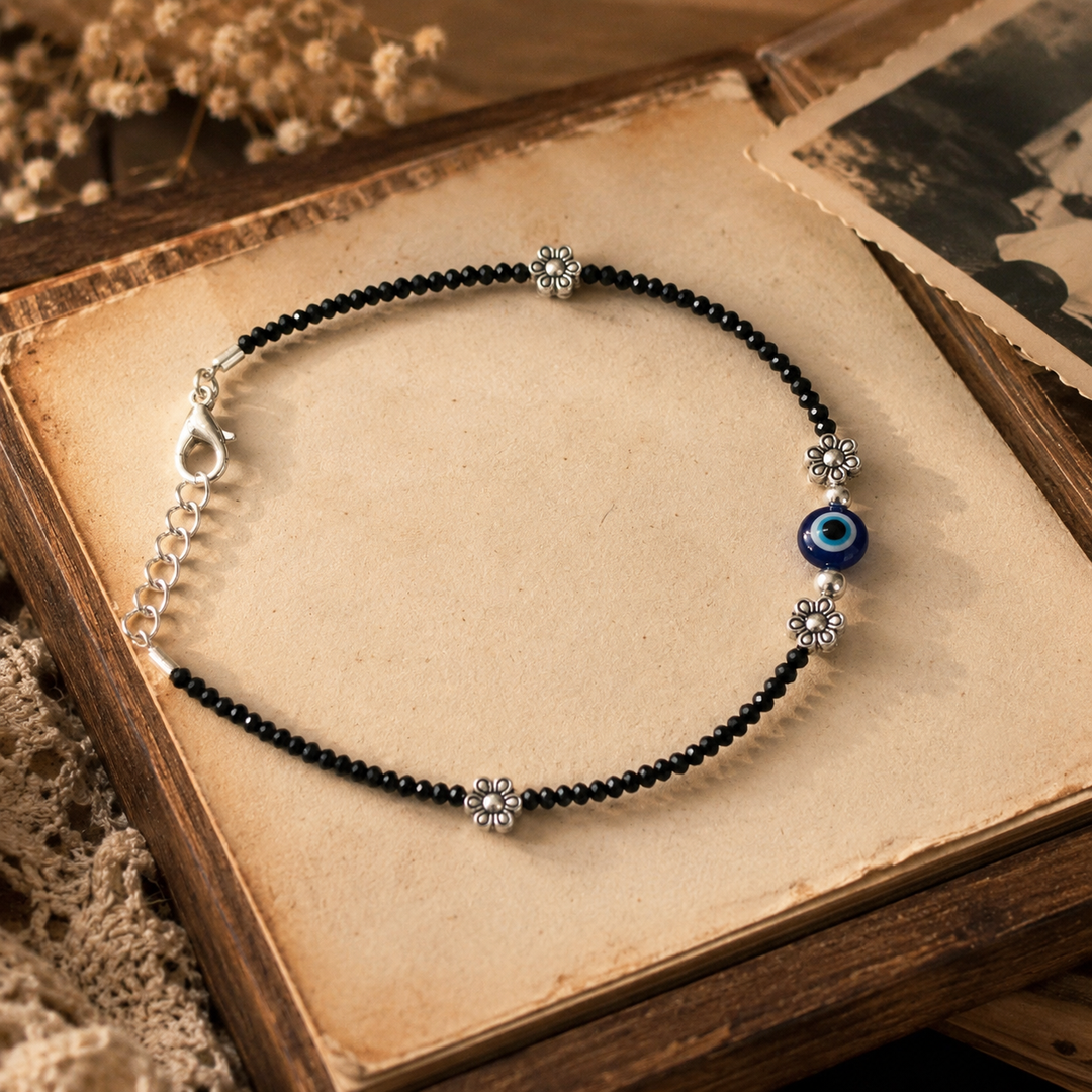 Retro Evil Eye black crystal beaded oxidized silver anklet with floral charms, adjustable vintage boho payal for women, handcrafted minimalist ethnic fashion jewelry.